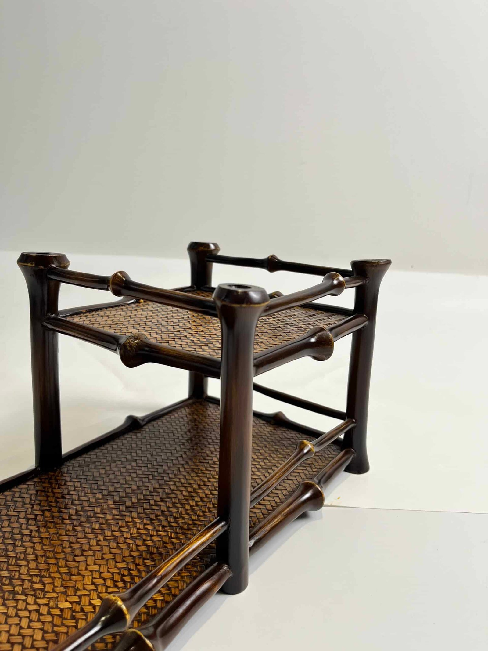 A compact, 2-tier bamboo tea shelf named the "Qiong Bamboo Tea Shelf - Teaware Organizer & Display Stand" is set against a plain background. It features dark wooden supports with woven panels, showcasing its handcrafted aesthetic.