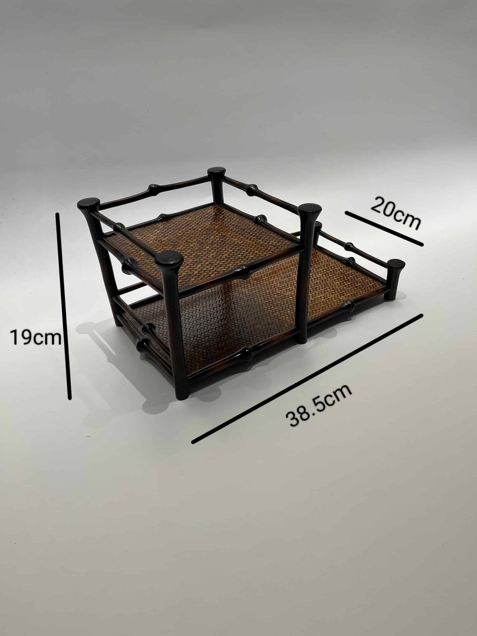 A two-tier Qiong Bamboo Tea Shelf with a black frame and woven brown mesh, measuring 38.5 cm in length, 20 cm in width, and 19 cm in height, designed for organizing and displaying teaware.