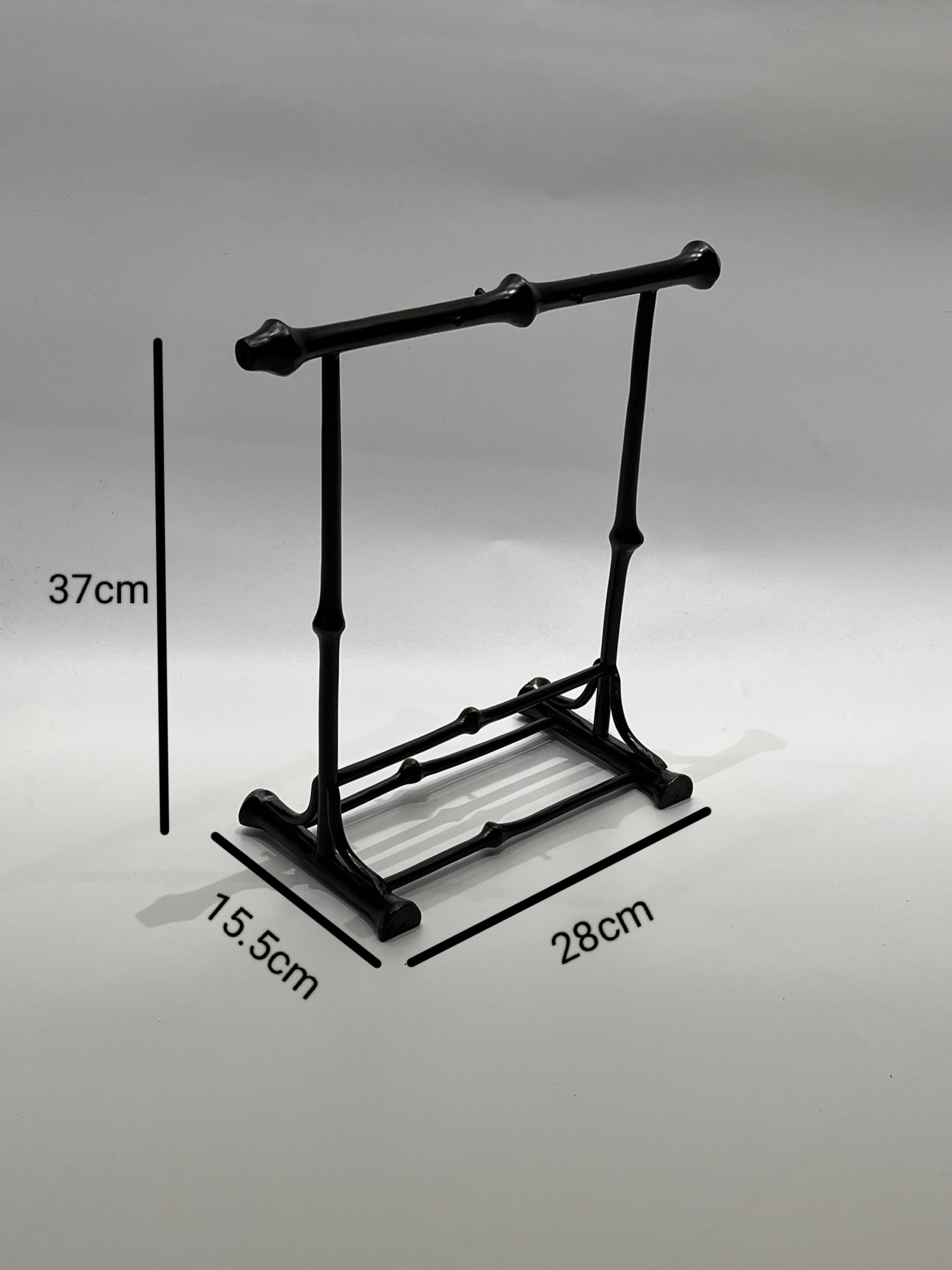 Introducing the Chinese Calligraphy Brush Pen Rack with 5 Hooks from Qiongzhu Bamboo. This sleek, black standing rack is crafted from metal, featuring two horizontal bars on a sturdy rectangular base. It measures 37cm in height, 28cm in width, and 15.5cm in depth. Its plain light gray background makes it ideal for beautifully showcasing your Chinese calligraphy tools.