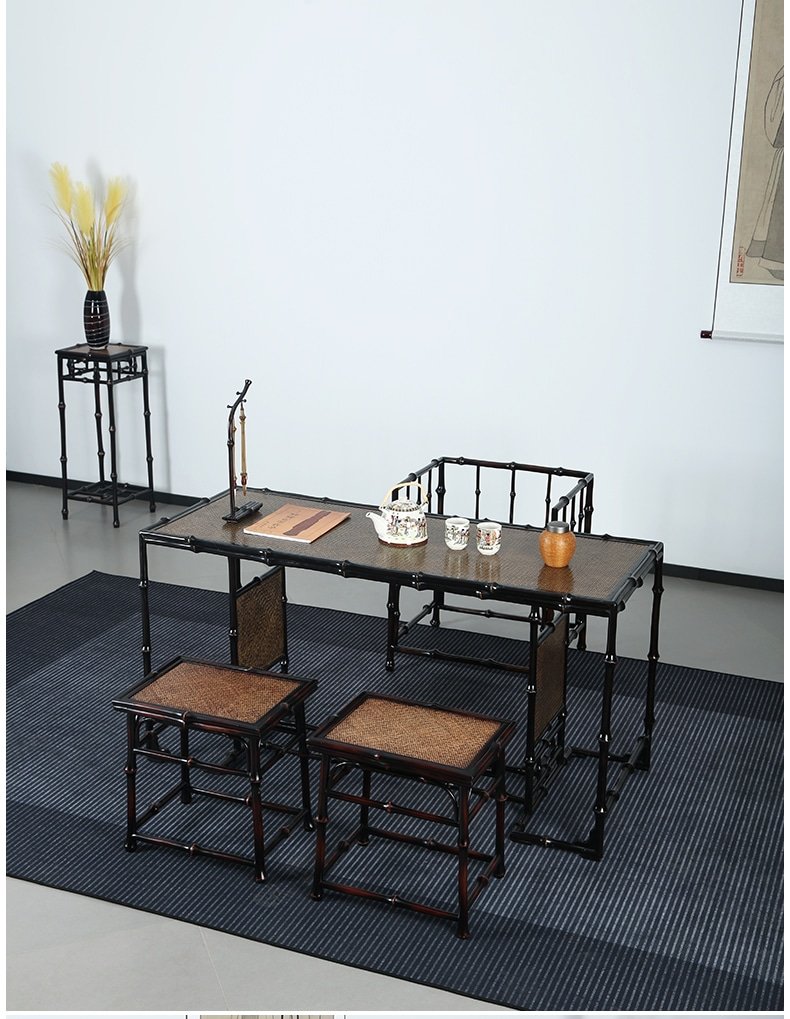 A minimalist tea room highlights a Handmade Chinese Qiongzhu Furniture bamboo table accompanied by chairs on a striped rug. The table is tastefully arranged with a teapot, cups, and a decorative tray. In the background, pampas grass graces a small side table against the white wall, capturing the spirit of Qiongzhu design.
