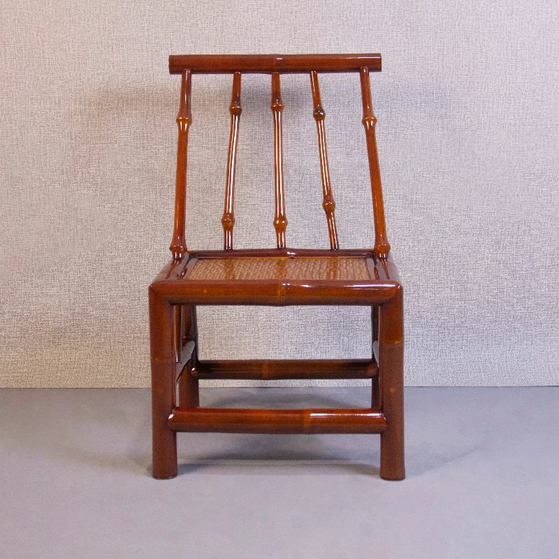 A Home Use Qiongzhu Bamboo Armless Backrest Small Chair with a weaving mat seat, featuring three vertical spindles and a polished finish that gleams against the light gray textured wall on a plain floor, evocative of traditional Qiongzhu bamboo craftsmanship.