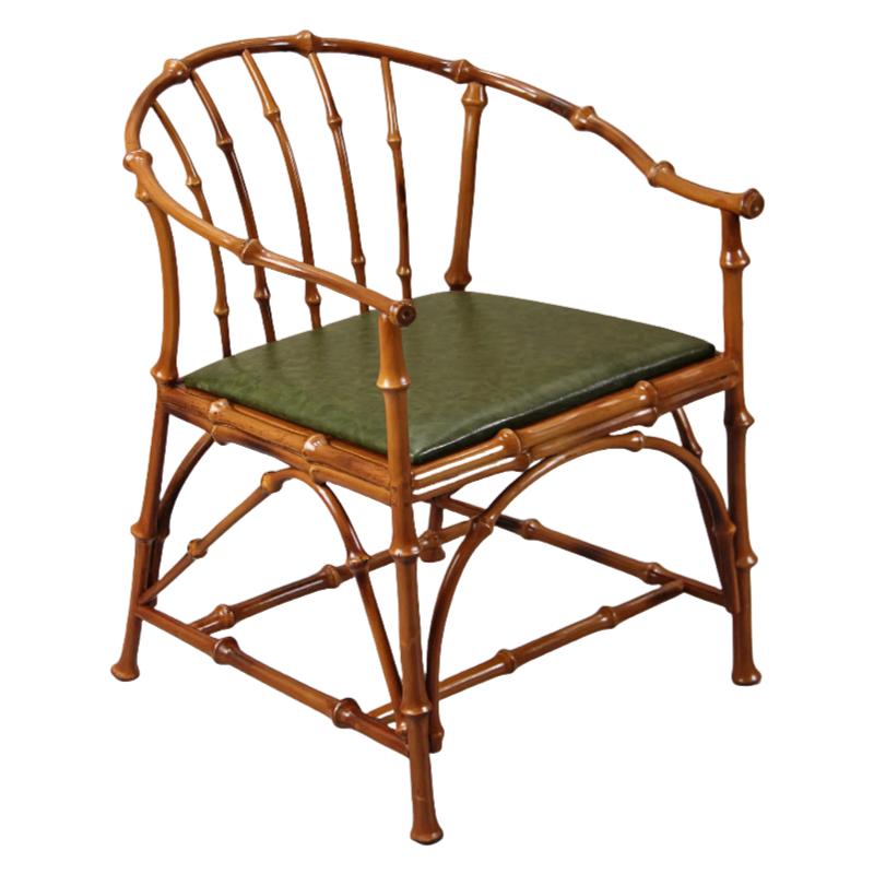 A chair with a bamboo frame and a green cushioned seat, featuring curved armrests and intricately designed legs.