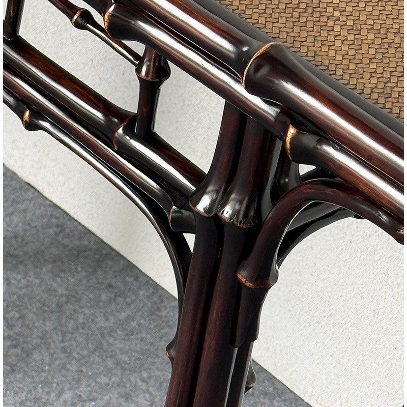 Close-up of a dark wooden table with bamboo-inspired leg design and a woven surface. The texture of the wood is glossy and smooth, and the woven top adds a natural, rustic touch.