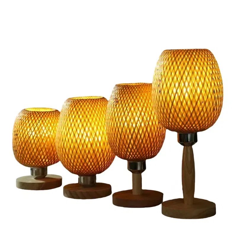 Four woven rattan lamps, decreasing in size from right to left, emit a warm, golden glow. Each lamp has a wooden base, creating a cozy ambiance against a plain background.
